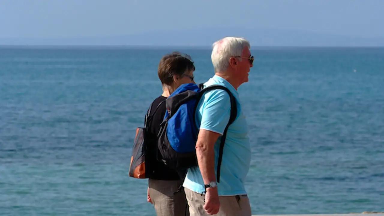 Dos personas mayores paseando por la playa Dos personas mayores paseando por la playa