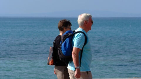 Dos personas mayores paseando por la playa