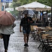 Varias personas se resguardan de la lluvia con paraguas en Madrid.