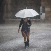 Una persona camina con un paraguas bajo la lluvia.