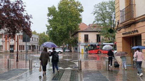 Gente con paraguas junto a la Puerta de los M&aacute;rtires de Alcal&aacute; de Henares