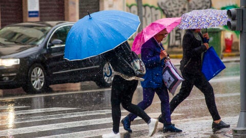 Personas se protegen de la lluvia en una calle