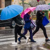 Personas se protegen de la lluvia en una calle Personas se protegen de la lluvia en una calle
