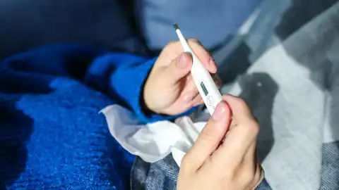 Imagen de archivo de una persona con un termómetro Expertos esperan una vuelta a la normalidad de la gripe con un solo pico en todo el invierno
