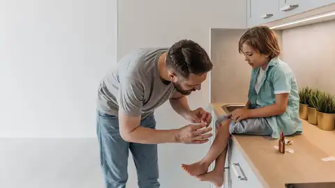 Padre cura una herida a su hijo Padre cura una herida a su hijo