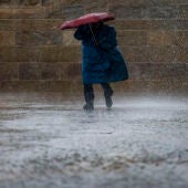 Un peregrino bajo la lluvia en la plaza del Obradoiro en Santiago de Compostela