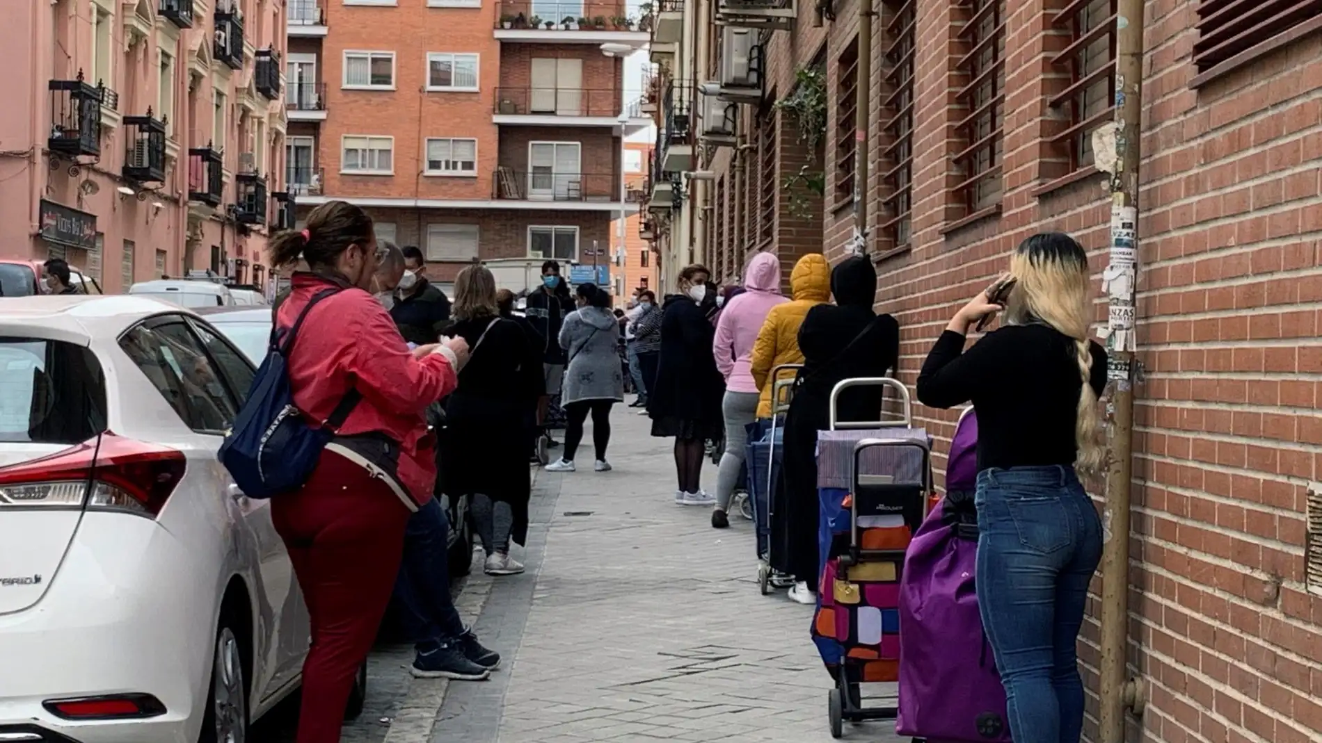 Imagen de archivo de varias personas esperando su turno para entrar al economato de Cáritas en Madrid