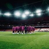 Los jugadores del Sevilla se reúnen sobre el césped del Emirates Stadium.