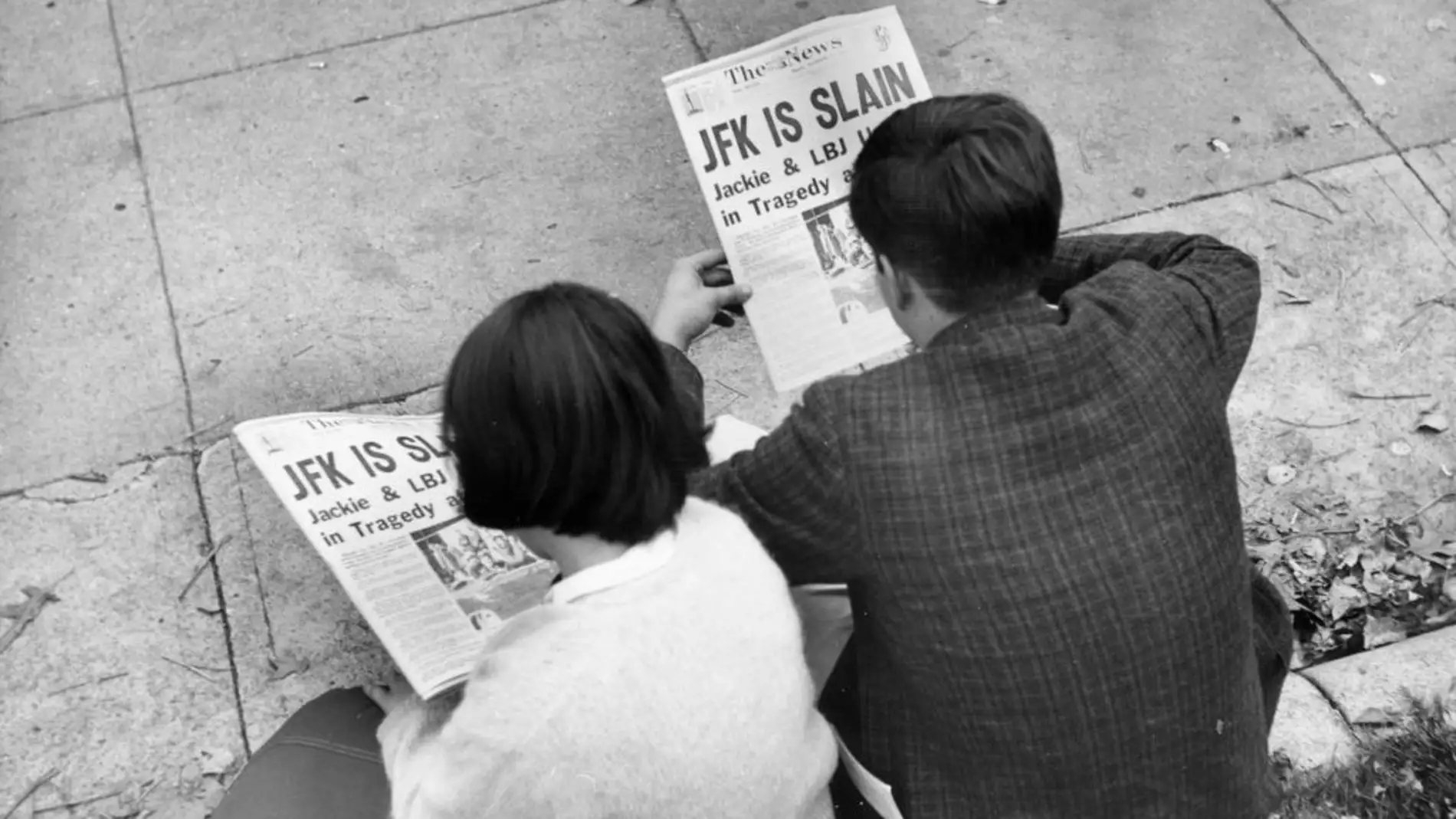 Dos personas leen en el periódico la noticia del asesinato de Kennedy 