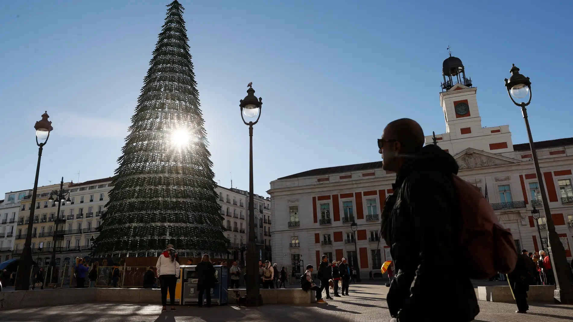 El sol asoma a través del árbol de Navidad instalado en la Puerta del Sol en Madrid.