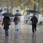 Un grupo de personas caminan bajo la lluvia en la Plaza de Europa de Gijón