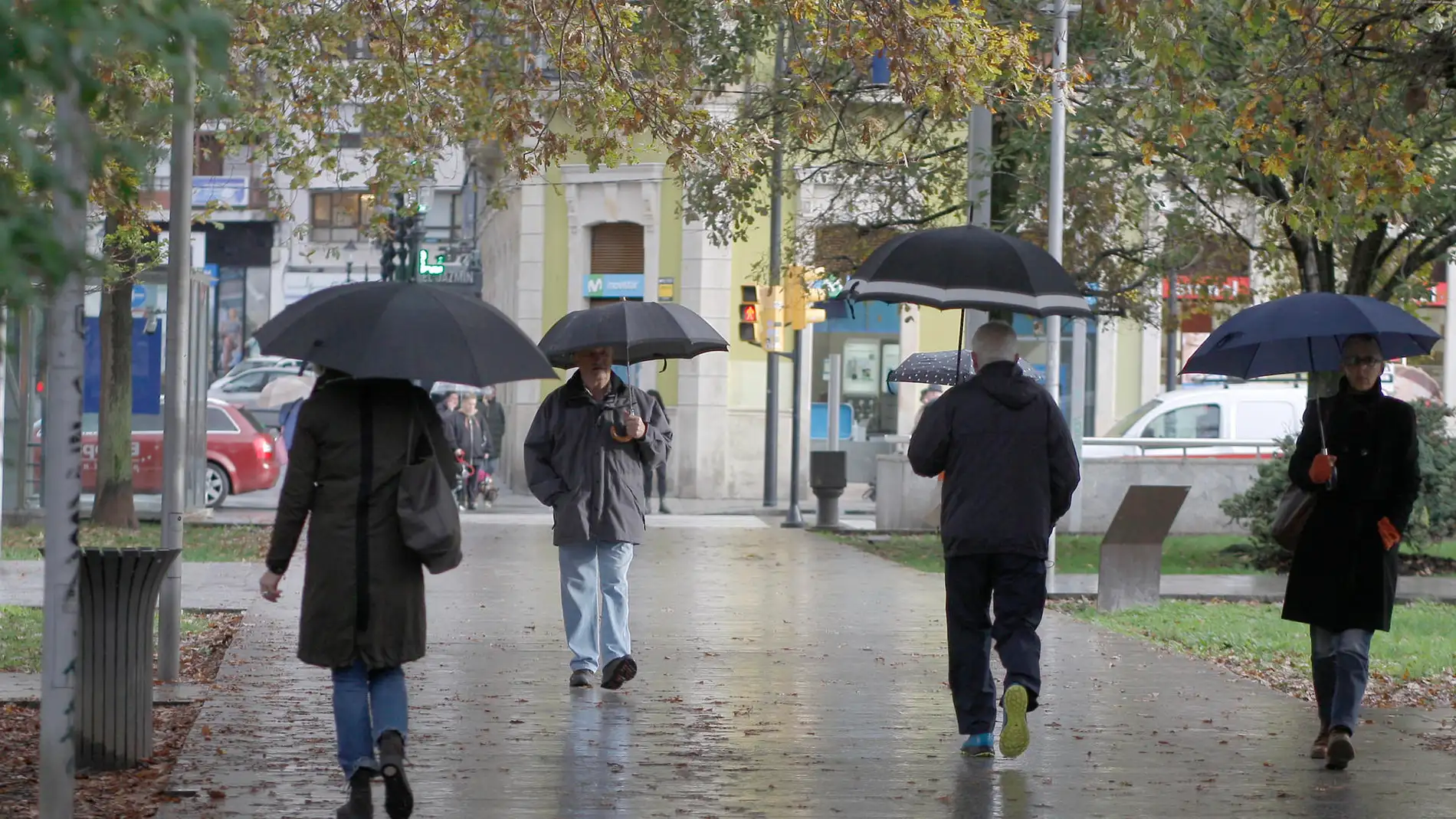 Un grupo de personas caminan bajo la lluvia en la Plaza de Europa de Gijón