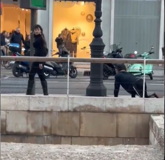 Una joven pasea a un hombre con una correa de perro por el centro de València Una joven pasea a un hombre con una correa de perro por el centro de València