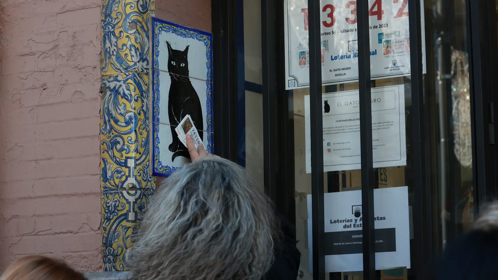 Una persona frota un décimo de Lotería de Navidad recién comprado en la Administración de Loterias del Gato Negro de Sevilla