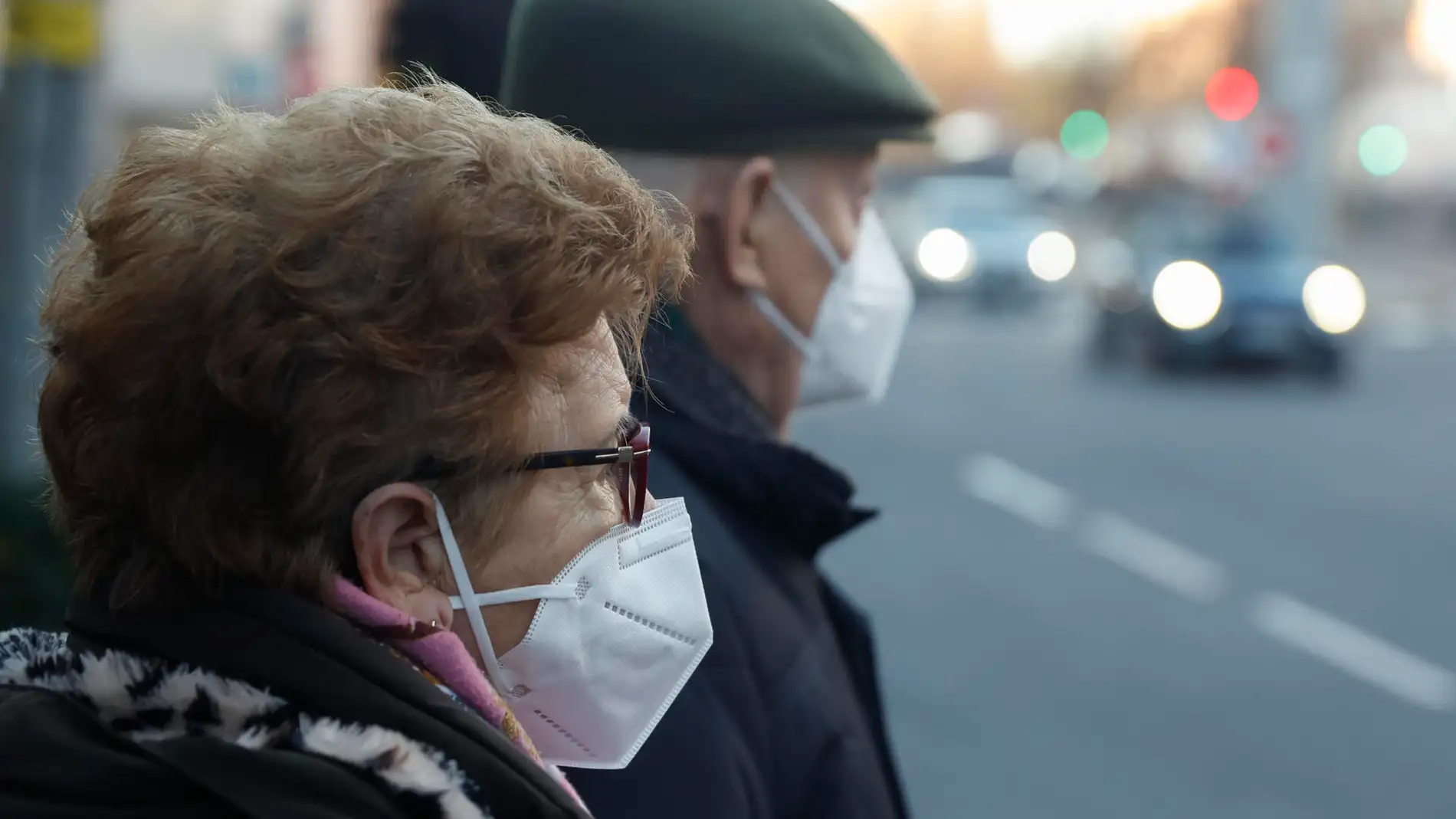 Una pareja de ancianos con mascarillas esperando para cruzar una calle en Madrid