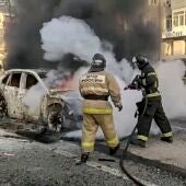 Bomberos rusos extinguiendo un coche en llamas después de un bombardeo en Belgorod. 