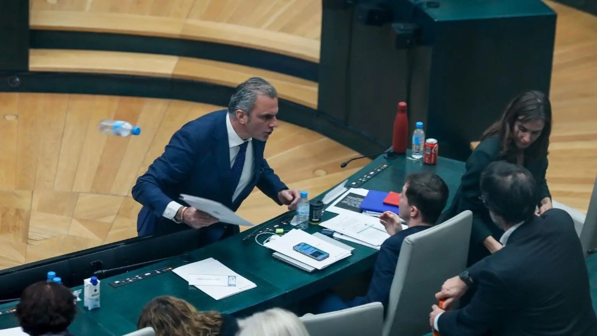 Momento en el que el portavoz de Vox en el Ayuntamiento de Madrid, Javier Ortega Smith, se encara y tira unos papeles y una botella de agua vacía al edil Eduardo Fernández Rubiño, concejal de Más Madrid, en su escaño.