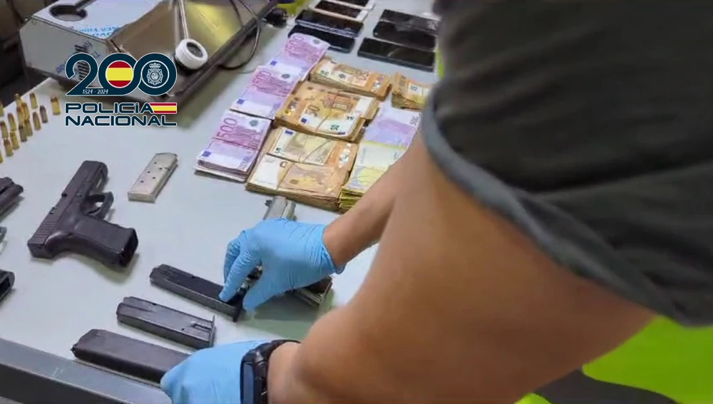 Un agente comprueba los cargadores de las pistolas; al lado, fajos con billetes de 500 euros