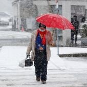 Un hombre se refugia de la nieve con un paraguas en una calle de Pedrafita do Cebreiro.