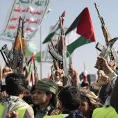 Un grupo de personas empuñan armas, ondean una bandera palestina y corean eslóganes durante una manifestación para conmemorar la muerte de diez combatientes hutíes a manos de la Marina estadounidense en el Mar Rojo. 