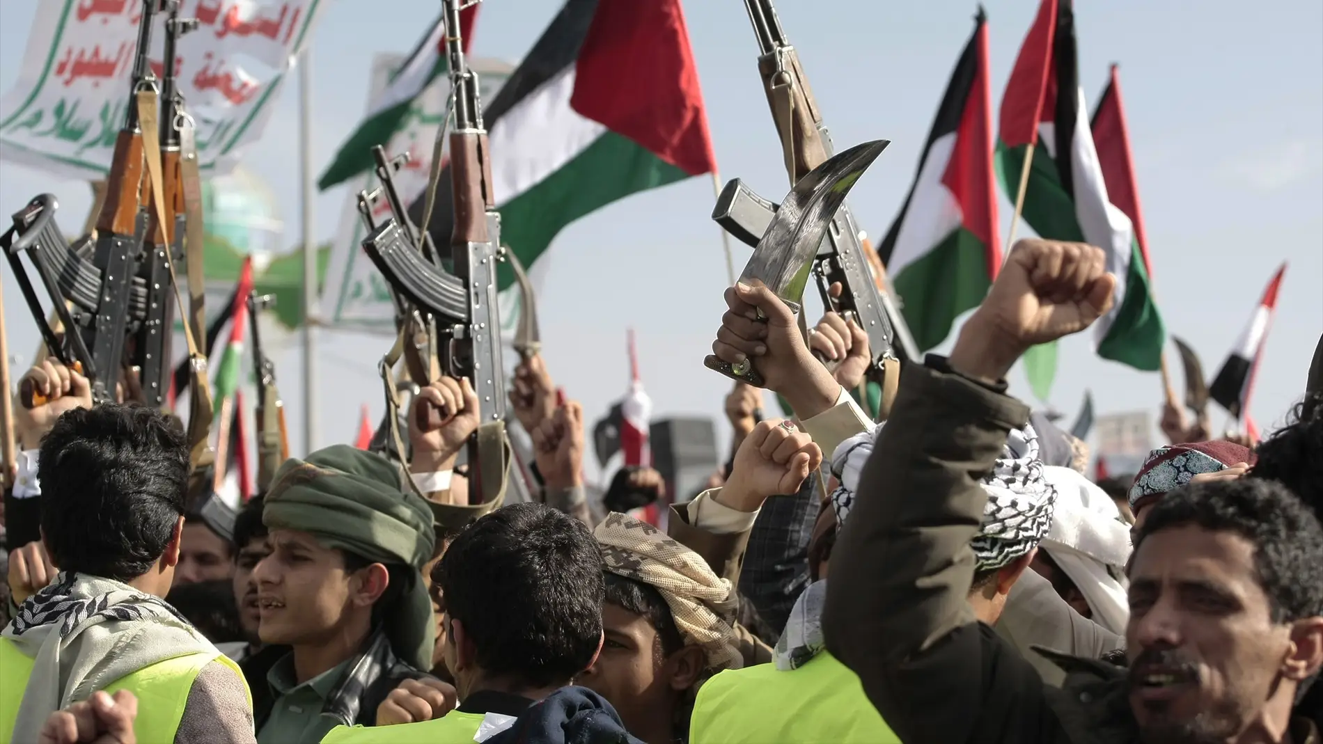 Un grupo de personas empuñan armas, ondean una bandera palestina y corean eslóganes durante una manifestación para conmemorar la muerte de diez combatientes hutíes a manos de la Marina estadounidense en el Mar Rojo. 
