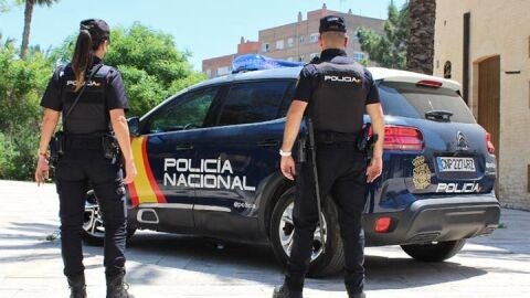 Imagen de archivo de unos agentes de la Policía Nacional al lado de su vehículo patrulla