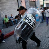 Un policía se retira con varios escudos después de choques entre policías y manifestantes en las afueras del Congreso en Ciudad de Guatemala