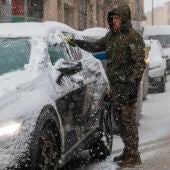 Un hombre retira la nieve de un vehículo durante la nevada en Soria.