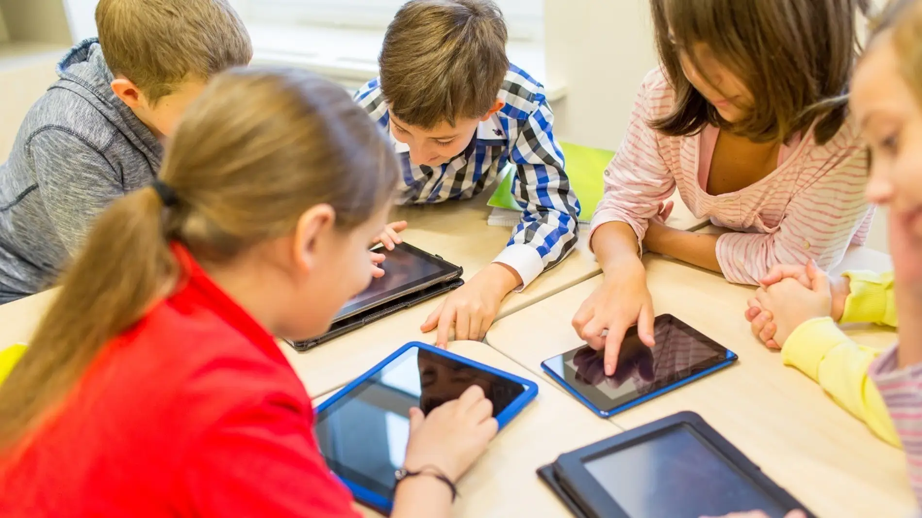 Imagen de archivo de varios niños usando tablets en un centro escolar.