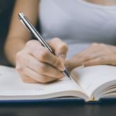 Una mujer escribiendo en una libreta 