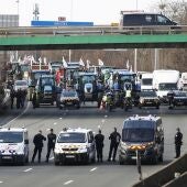  Agentes de policía se parapetan ante docenas de tractores de agricultores que bloquean cerca de la localidad francesa de Argenteuil la autopista de acceso a París A15 por el norte.