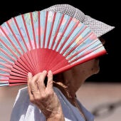 Una mujer se protege con un abanico del sol, en una fotografía de archivo.