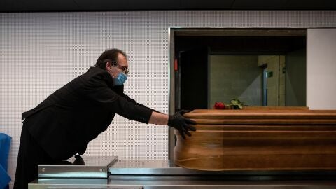 Un trabajador de una funeraria introduce un ataúd en un horno crematorio. 