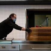 Un trabajador de una funeraria introduce un ataúd en un horno crematorio. 