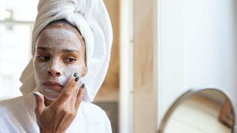 Una mujer poniéndose una mascarilla