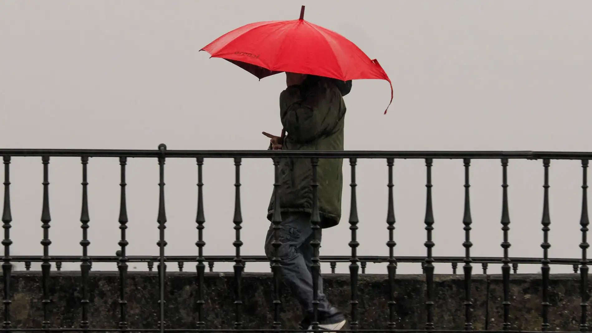 Un hombre camina con paraguas por el Puente de la Misericordia, en Viveiro, Lugo