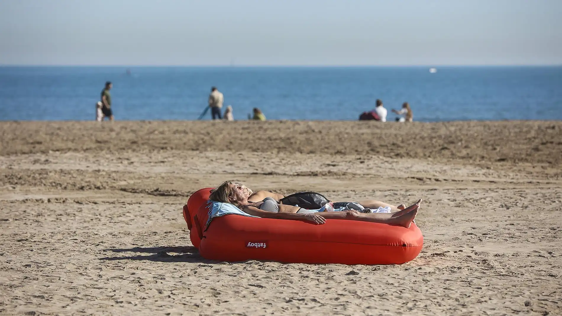 Una mujer toma el sol tumbada en un flotador, en la playa de la Malvarrosa, a 25 de enero de 2024