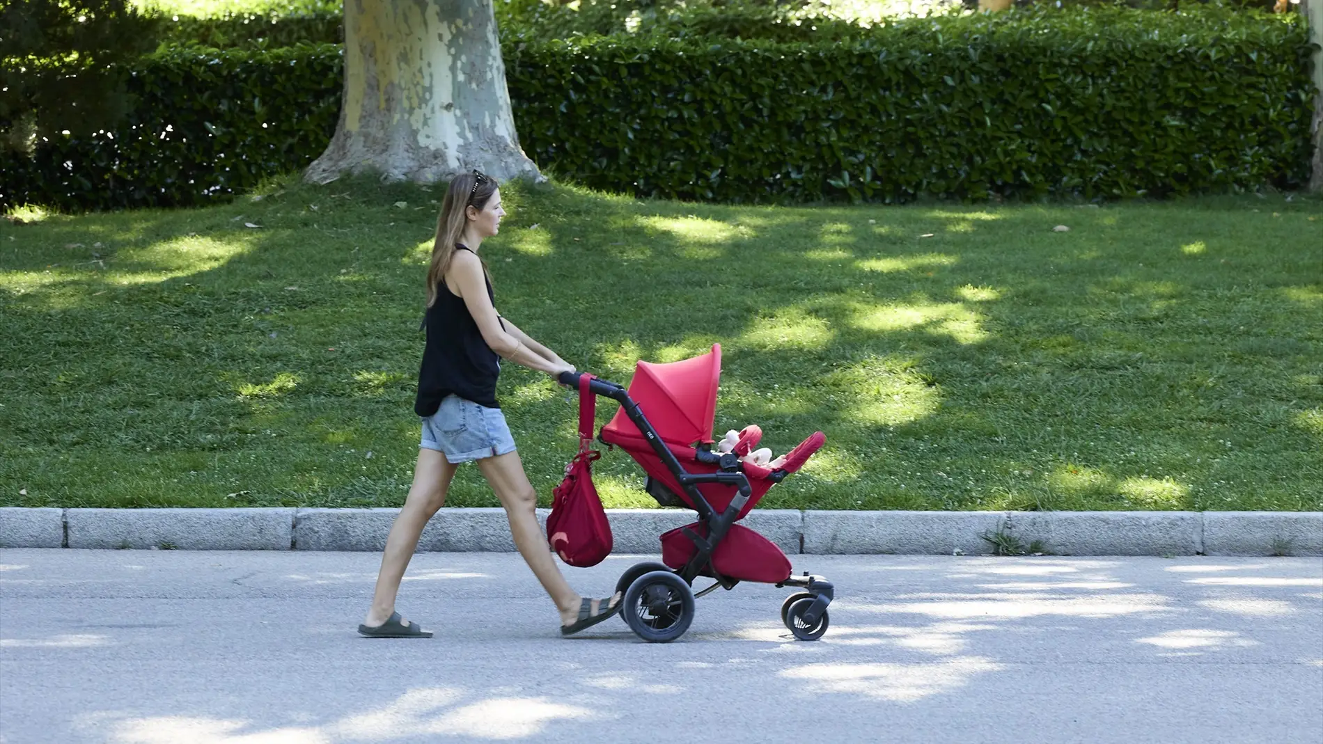 Una persona pasea con un carrito de bebé en el parque de El Retiro, a 29 de julio de 2023/ Jesús Hellín / Europa Press