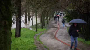 Personas paseando por una zona afectada por el desbordamiento del río Arga en Pamplona.