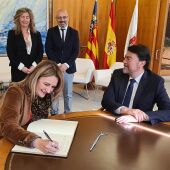 La consellera Nuria Montes firma en el libro de honor del ayuntamiento ante el alcalde Luis Barcala
