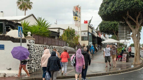 Turistas pasean por Puerto del Carmen, Lanzarote (Canarias) en un día con alerta meteorológica por DANA 24/03/2024