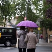 Varias personas con paraguas pasean por una de las calles de Barcelona.