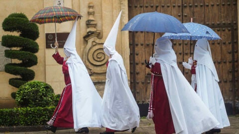 Unos nazarenos de la Hermandad de La Sentencia se protegen de la lluvia