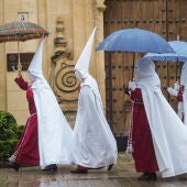 Unos nazarenos de la Hermandad de La Sentencia se protegen de la lluvia