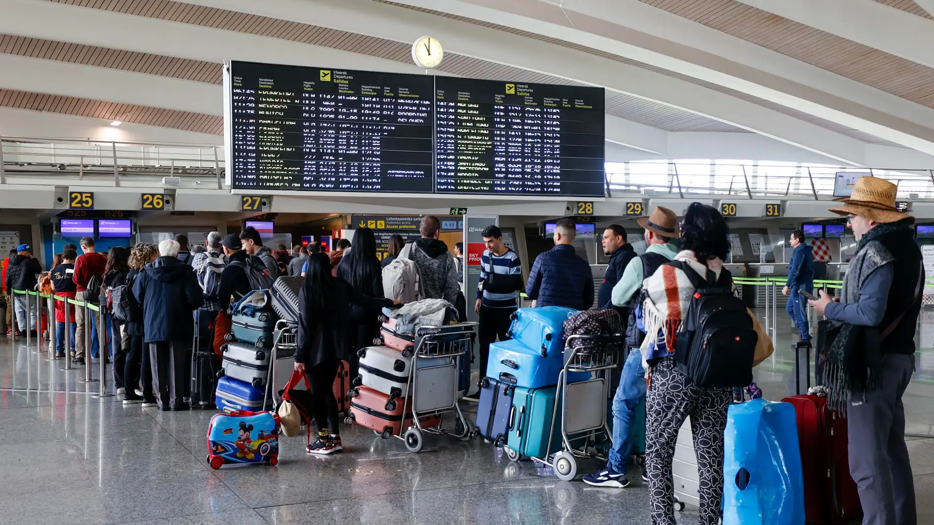 Viajeros hacen cola para facturar sus maletas en el aeropuerto de Bilbao.
