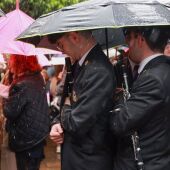 Imagen de músicos guarecidos bajo paraguas durante la Semana Santa de Sevilla 2024