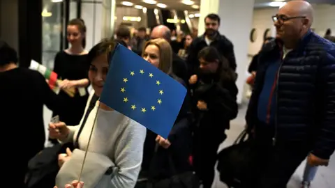 Una persona entrega banderas de la UE a los pasajeros que llegan en un vuelo procedente de Berlín durante la apertura simbólica del espacio Schengen en el aeropuerto de Sofía, Bulgaria, el 31 de marzo de 2024. Una persona entrega banderas de la UE a los pasajeros que llegan en un vuelo procedente de Berlín durante la apertura simbólica del espacio Schengen en el aeropuerto de Sofía, Bulgaria, el 31 de marzo de 2024.