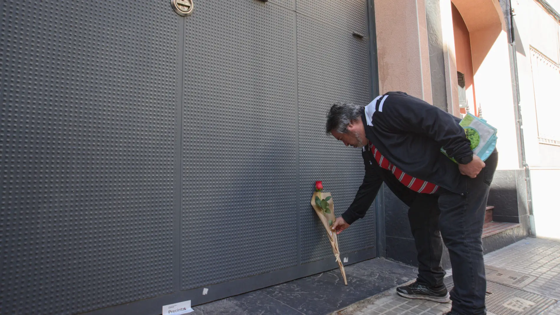Un hombre deposita una rosa en el garaje de la vivienda donde un hombre ha matado presuntamente a su mujer y sus dos hijos menores, 10 de abril de 2024, en El Prat de Llobregat,