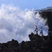 La Dirección General de Emergencias del Gobierno de Canarias ha declarado la situación de alerta, en todo el archipiélago, ante el riesgo de inundación costera por saltos del oleaje a paseos marítimos y carreteras próximos a la línea de costa durante la pleamar. En la imagen, turistas se saltan la prohibición de acercarse al mar, en Los Cancajos, en la isla de La Palma. 