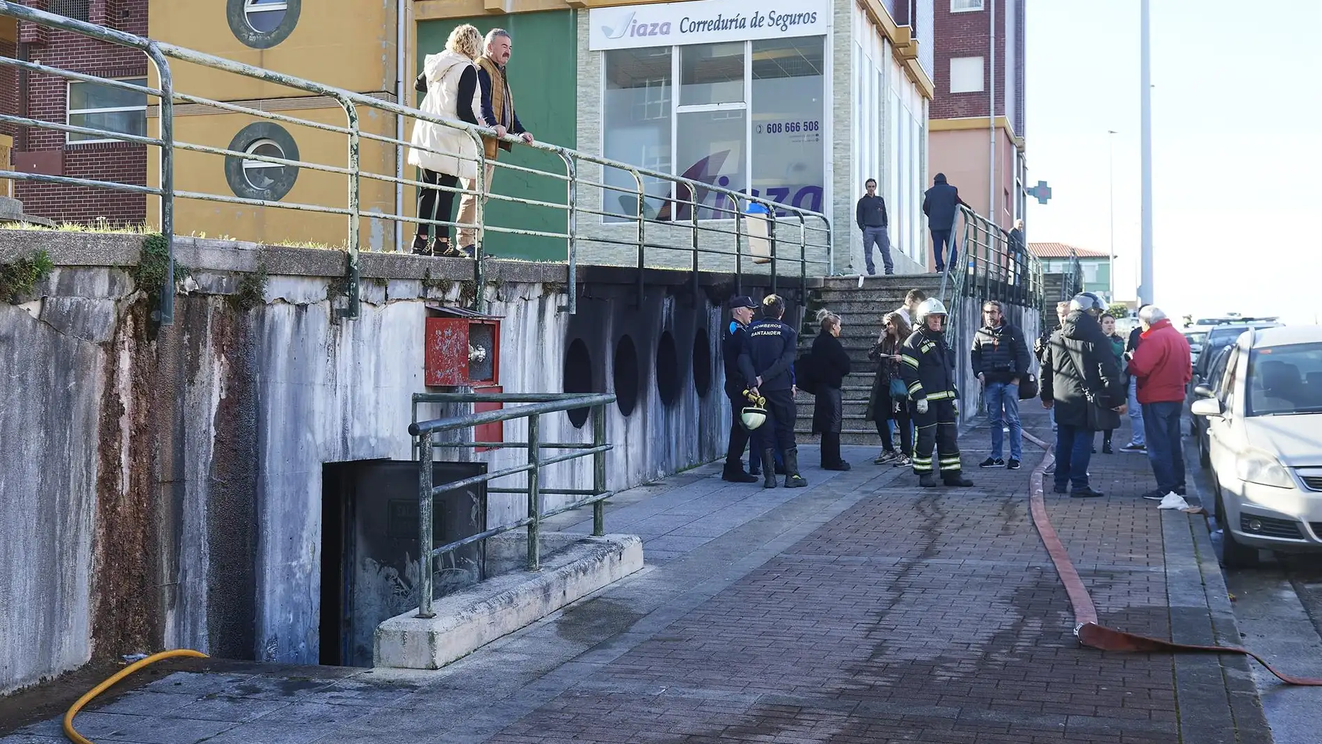 Bomberos y vecinos en las inmediaciones del incendio de un garaje comunitario en la calle José María Cossío